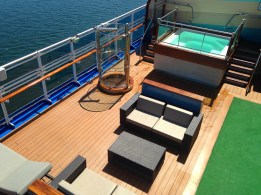 An isolated section of the deck features a modern square Jacuzzi and contemporary furniture. 